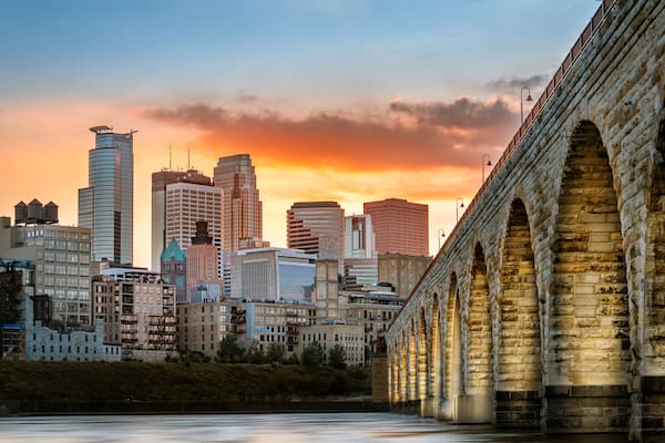 A city skyline with modern buildings and a historic stone bridge.