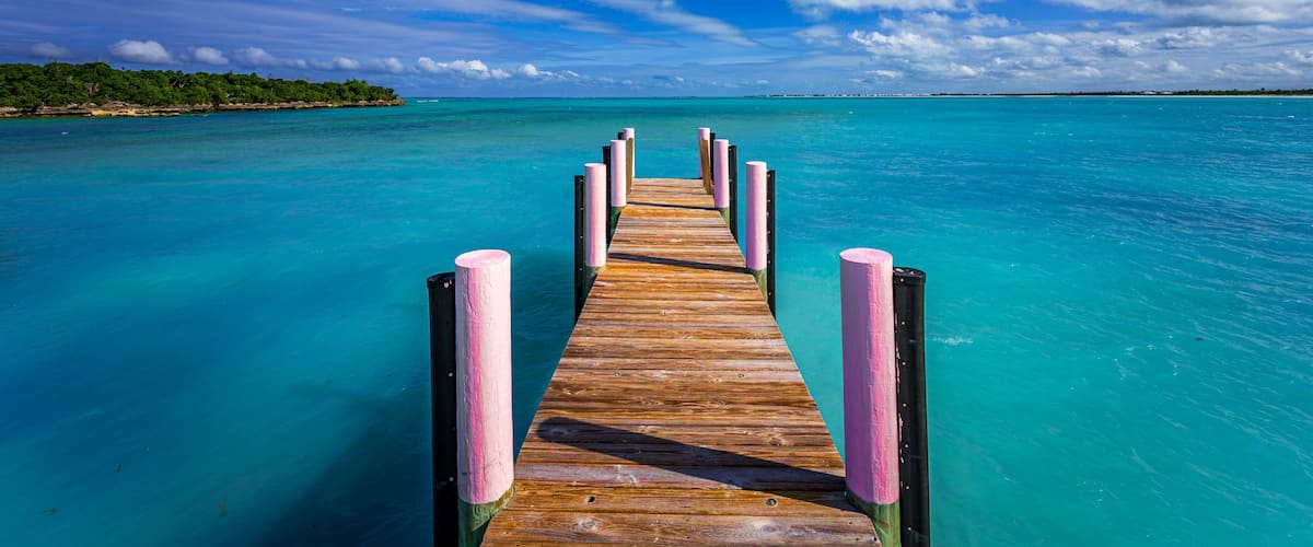 A wooden pier extending into turquoise waters with a clear sky above.