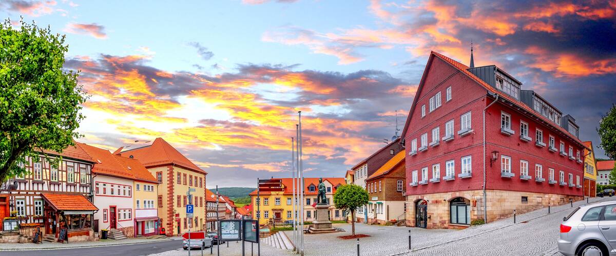 A European town with historic buildings, cobblestone streets, and a statue in the square.