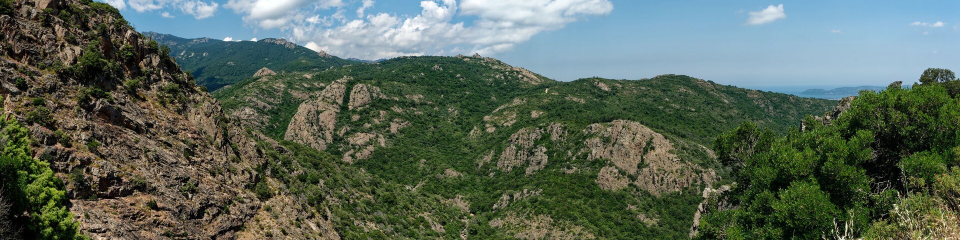 Eine gebirgige Landschaft mit felsigem Gelände und dichtem Grün.