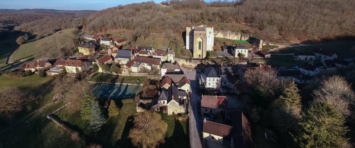 An aerial view of a historic town with a prominent church and surrounding houses.