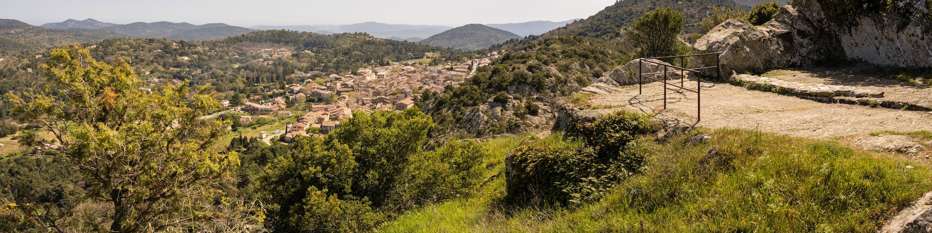 A mountainous landscape with a village nestled in the valley, surrounded by dense forests and rocky terrain.
