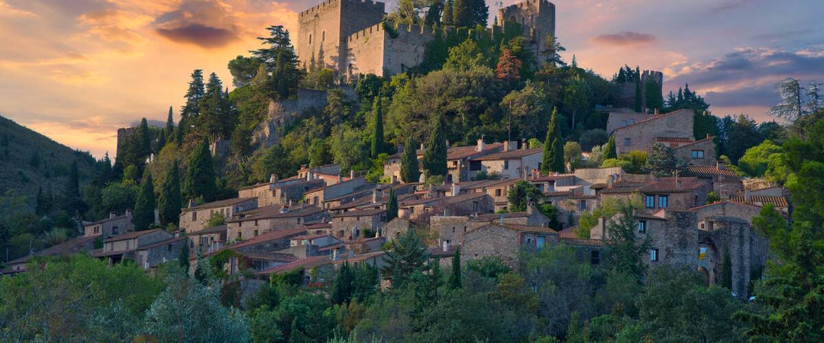 A medieval castle atop a hill, surrounded by a village with traditional stone houses.