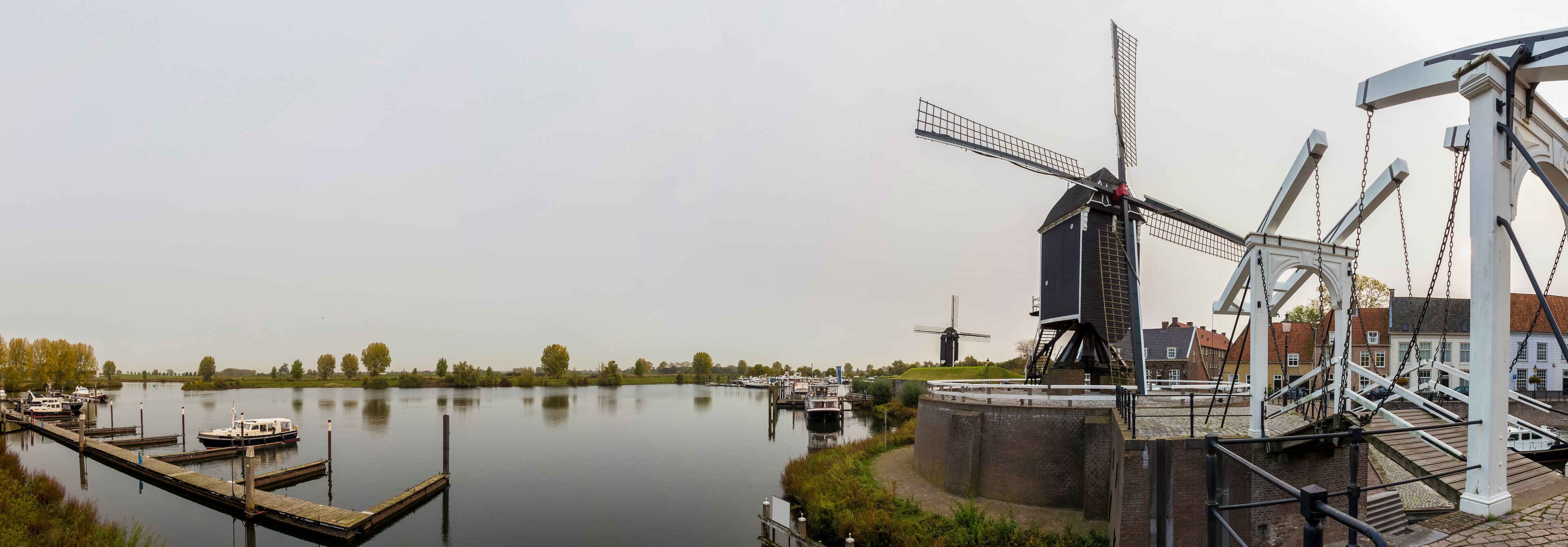 A canal with boats, a windmill, and a watermill.