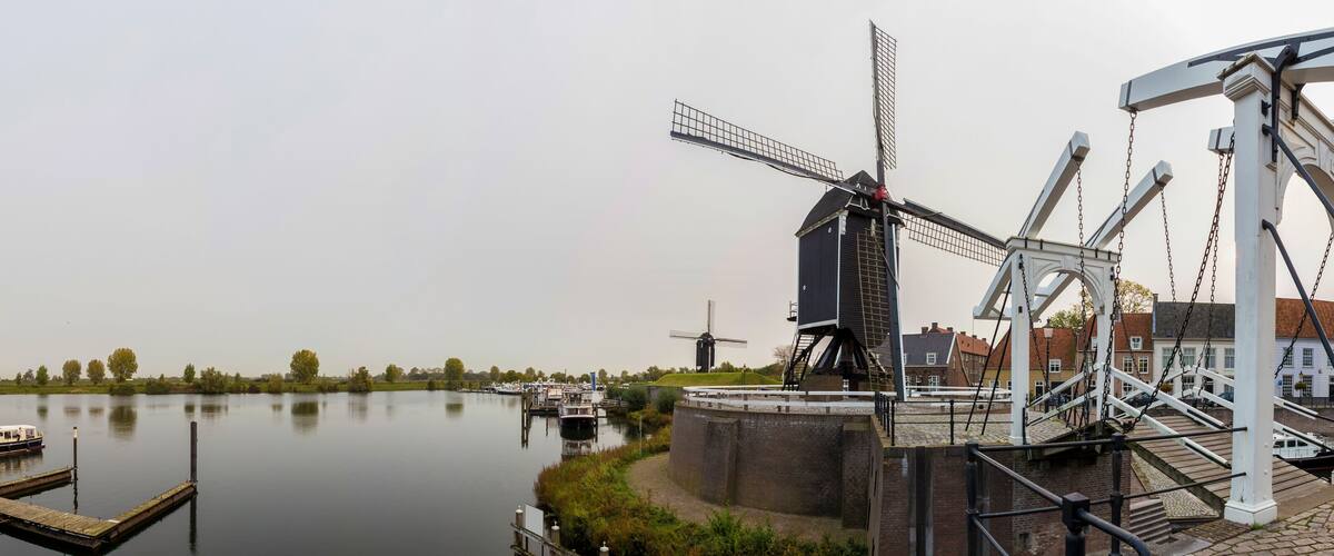 A canal with boats, a windmill, and a watermill.