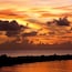 A sunset over a body of water with a rocky shoreline.