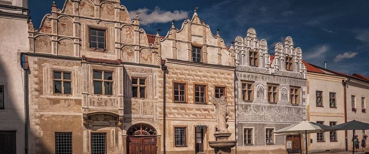 A historic building with ornate architecture and a statue in the courtyard.