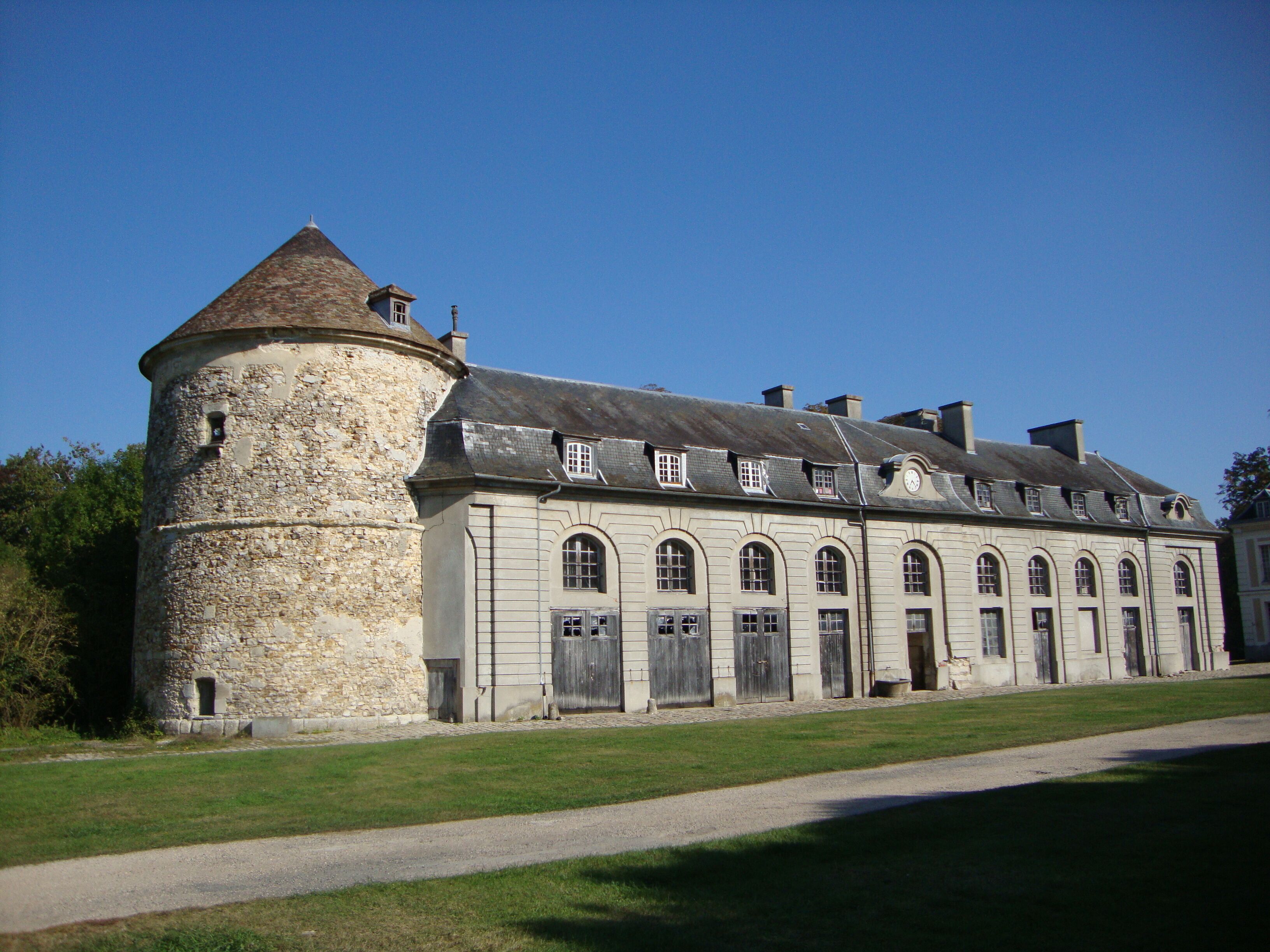 A historic stone building with a round tower and arched windows.