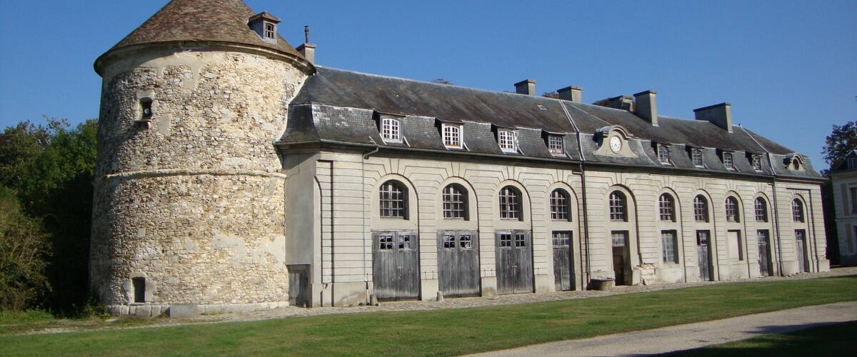A historic stone building with a round tower and arched windows.