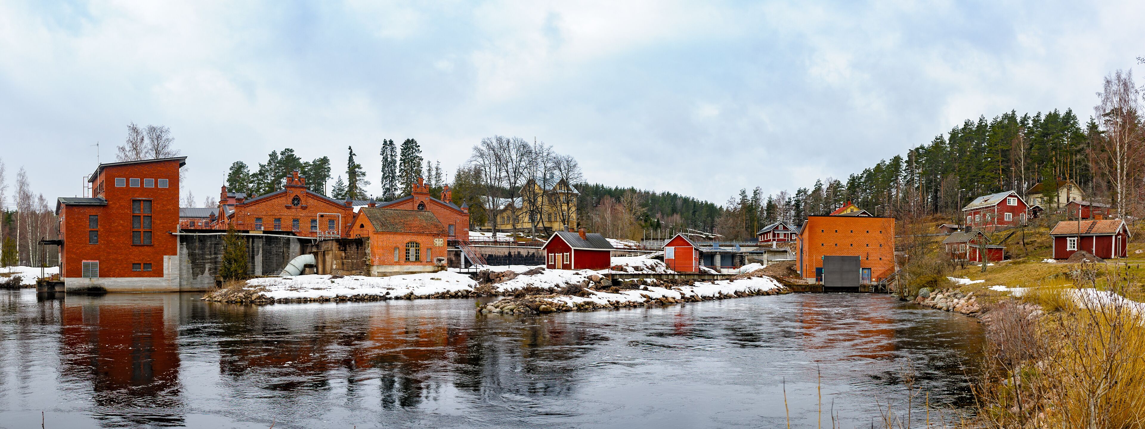 A river with buildings and trees in a snowy landscape.
