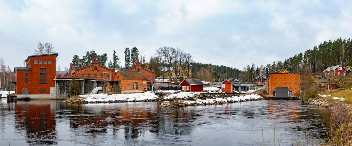 A river with buildings and trees in a snowy landscape.