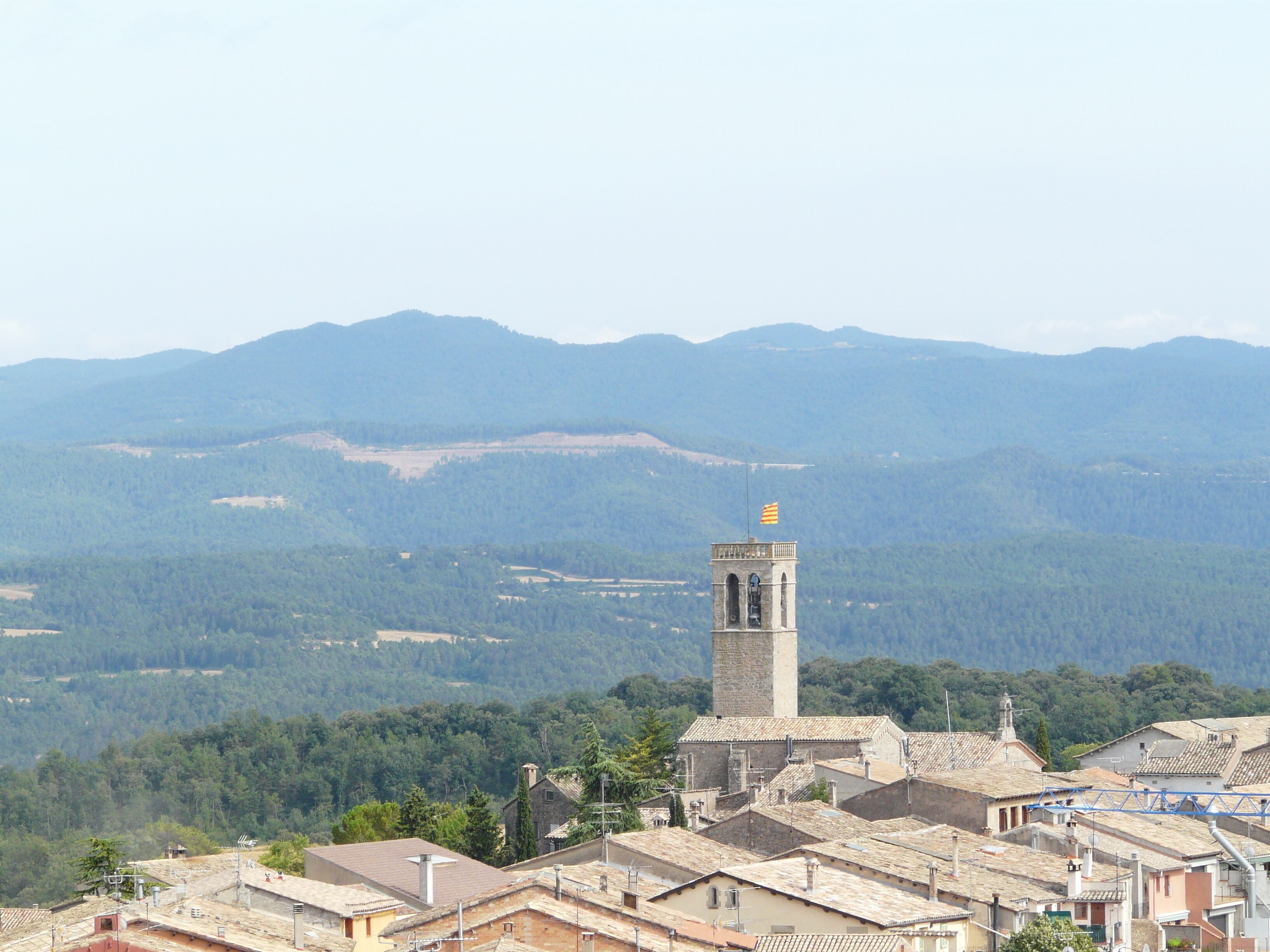 A town with a prominent tower and surrounding mountains.
