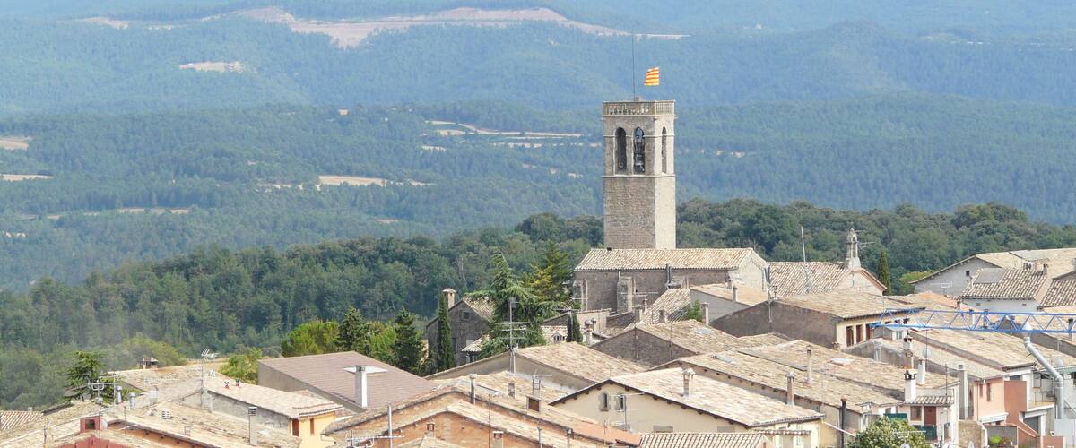 A town with a prominent tower and surrounding mountains.