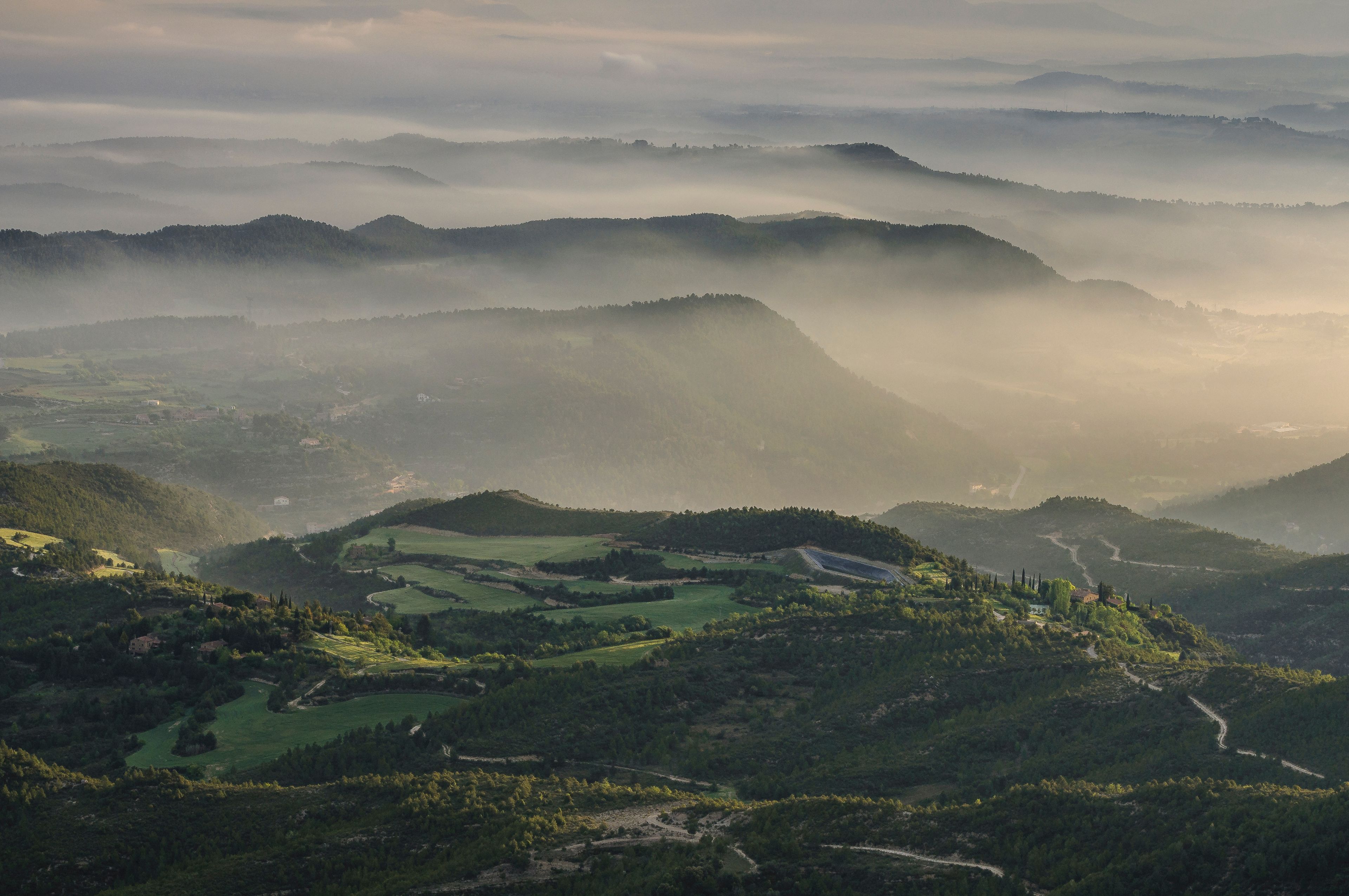 Un paisaje montañoso con colinas ondulantes, valles y un río serpenteante.