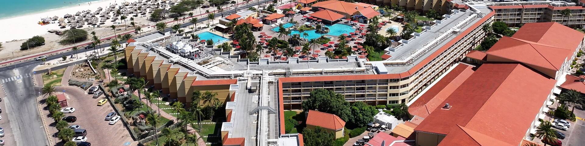 A coastal resort with a beach, swimming pool, and hotel buildings.