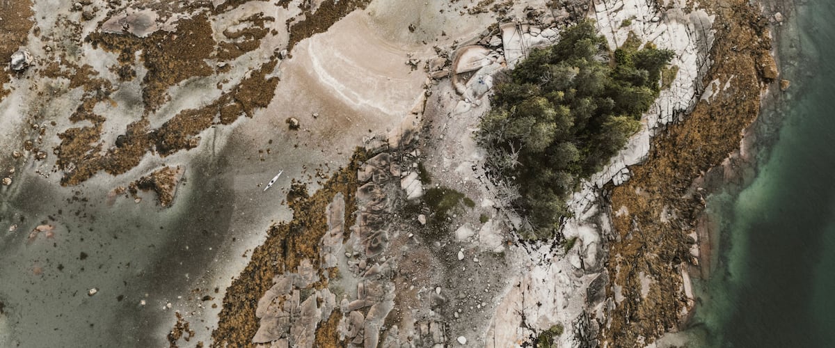 A coastal landscape with rocky terrain, sparse vegetation, and clear water.