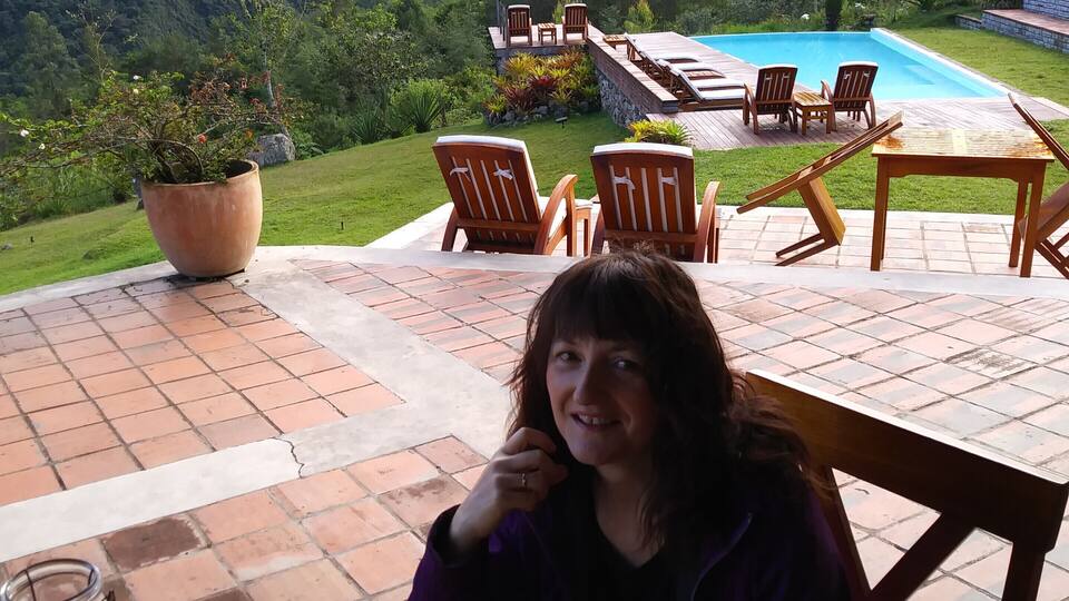 A person dining at an outdoor table with a scenic view of a mountainous landscape and a waterfall in the background.