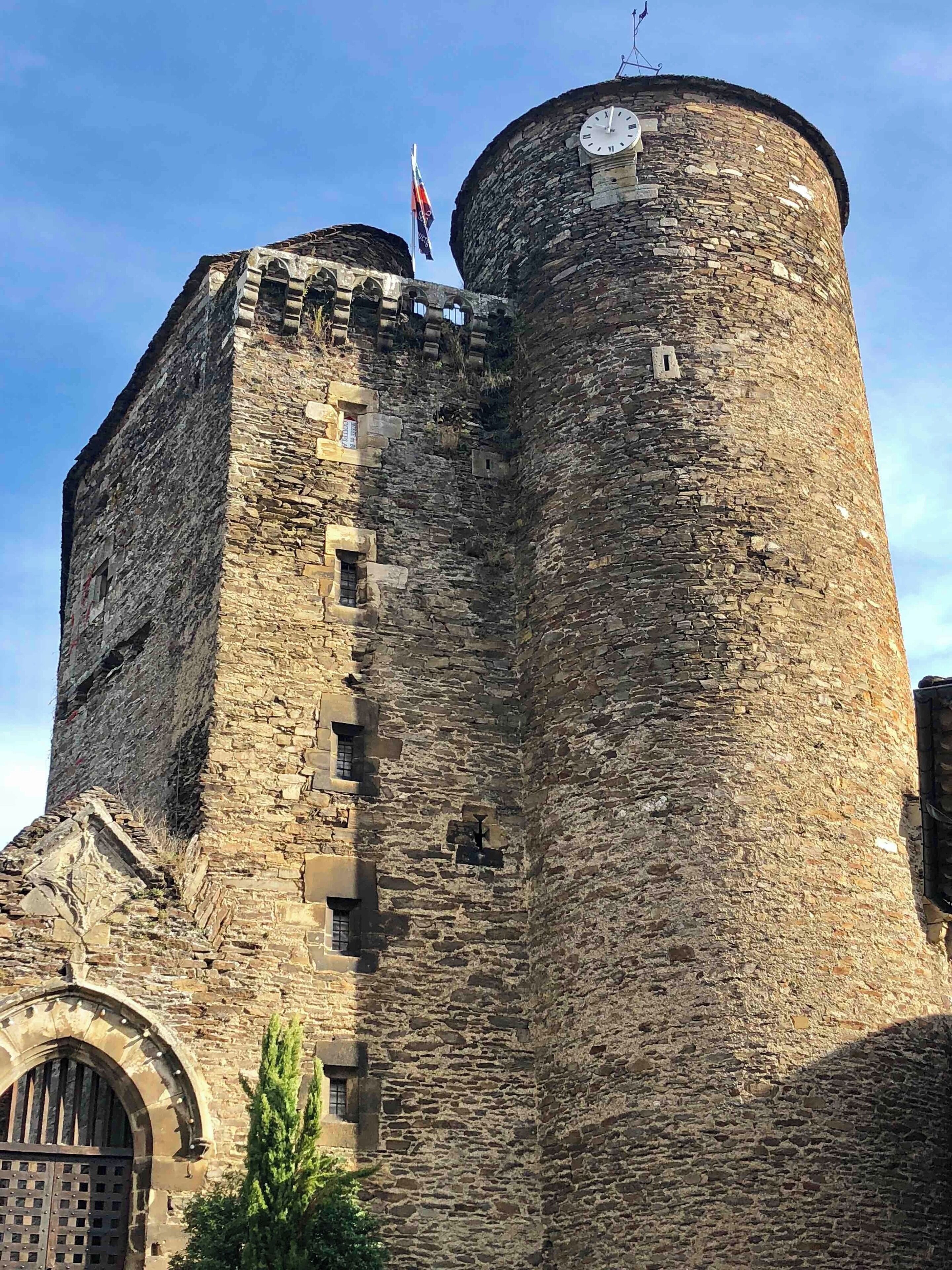 A historic stone castle with a round tower, arched windows, and a flag.