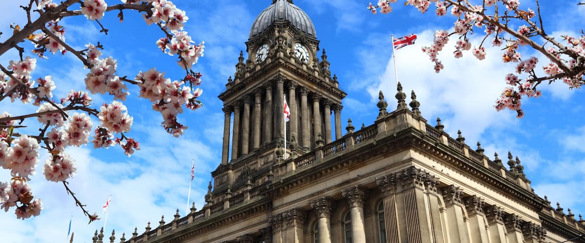 A grand neoclassical building with a prominent dome and columns, surrounded by blooming cherry blossoms.