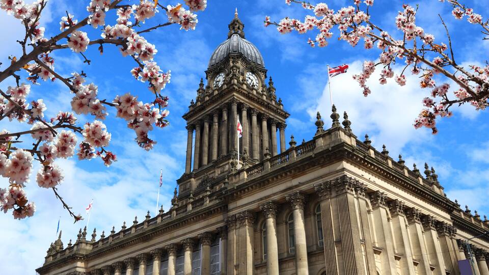 A grand neoclassical building with a prominent dome and columns, surrounded by blooming cherry blossoms.