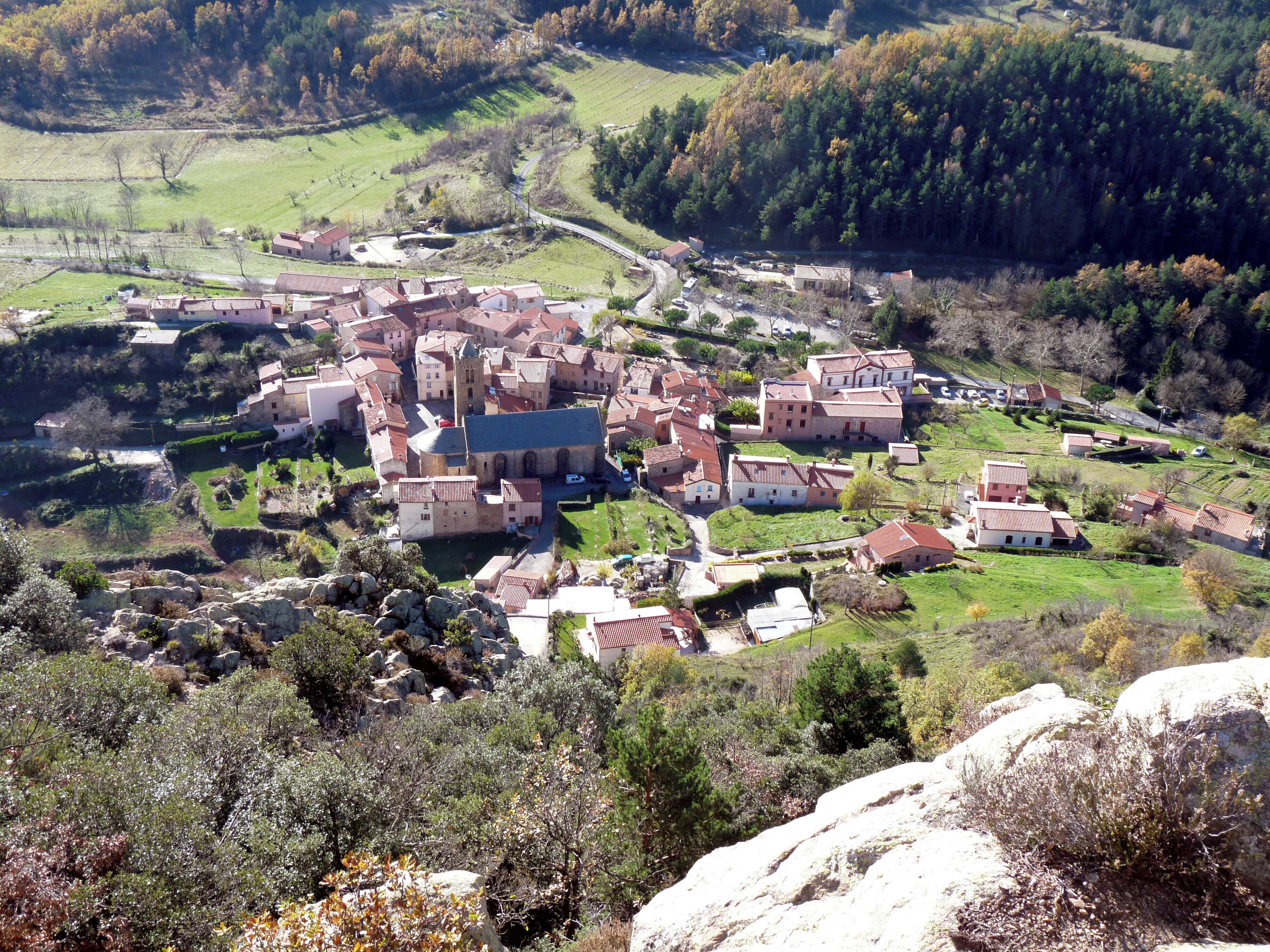 A village with a prominent church, surrounded by rolling hills and vineyards.