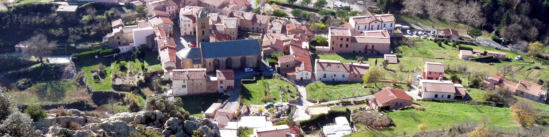 A village with a prominent church, surrounded by rolling hills and vineyards.