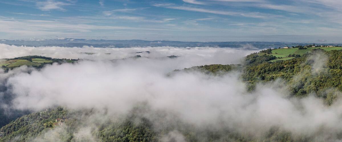 A valley with lush green hills and a blanket of clouds above.