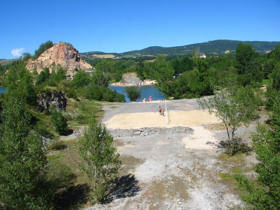 Uma colina rochosa, um lago e uma área arenosa com árvores.