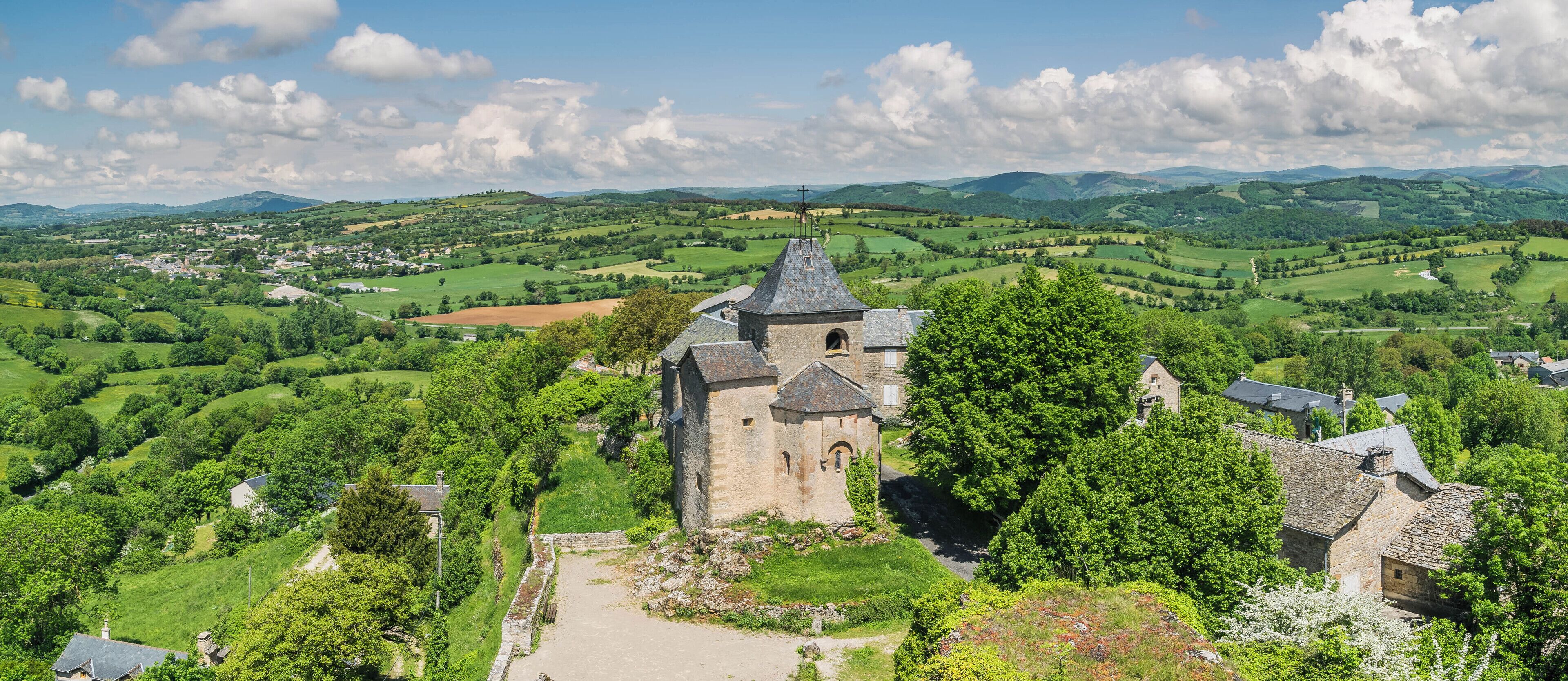 A historic stone tower surrounded by lush green fields and rolling hills.
