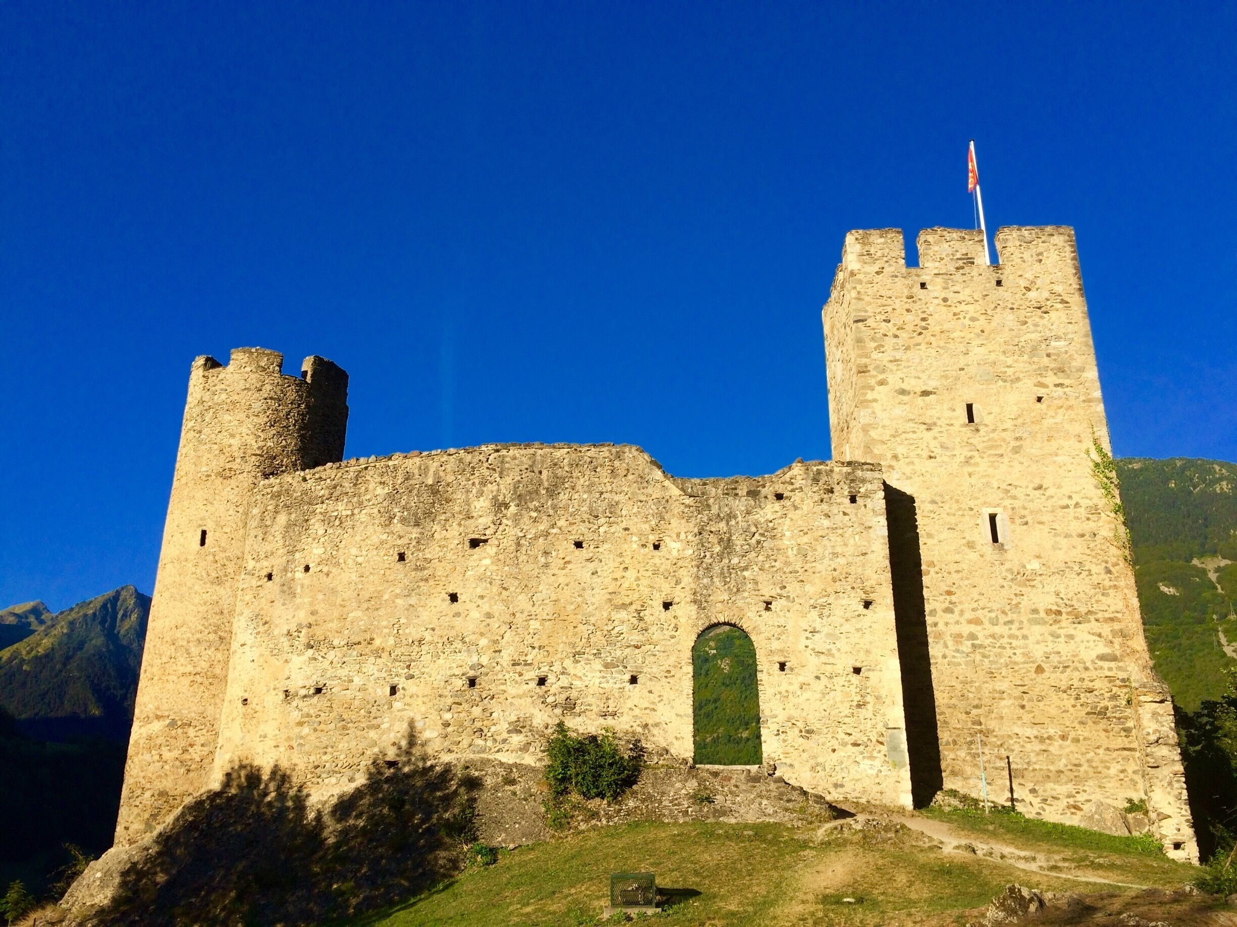 A medieval castle with two towers, a central arched entrance, and a flag on top.
