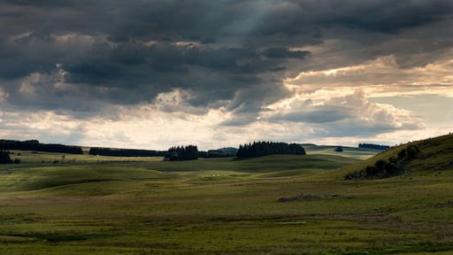panorama of the Aubrac plateau in the evening with dramatic storm clouds & sun rays, rustic rural scene, Lozere France