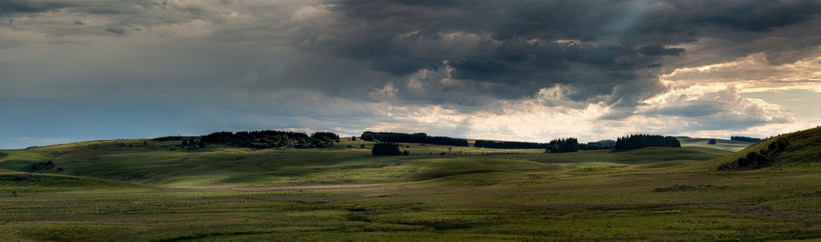 panorama of the Aubrac plateau in the evening with dramatic storm clouds & sun rays, rustic rural scene, Lozere France