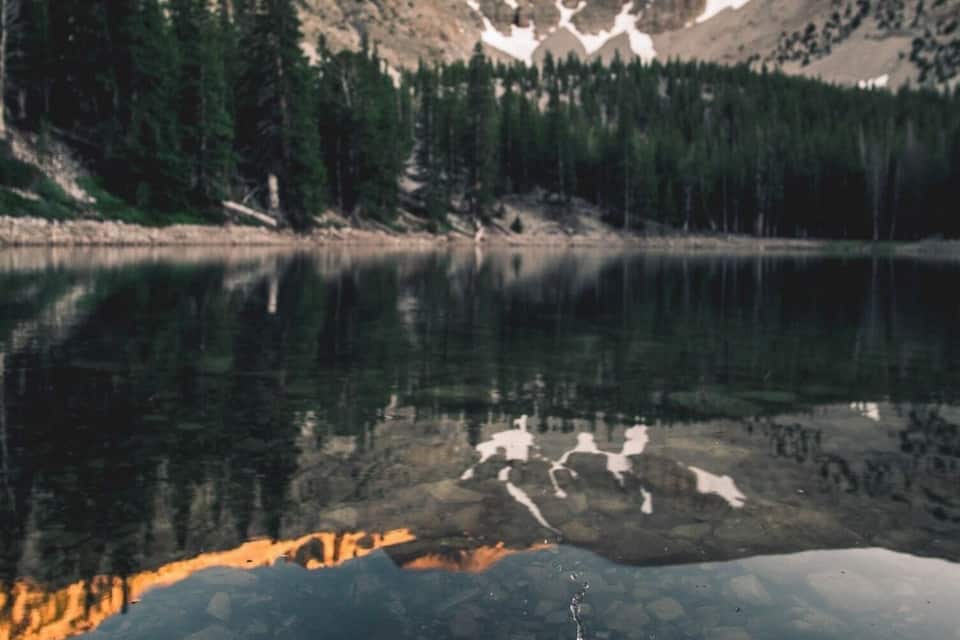 A mountain lake with reflections of trees and mountains.