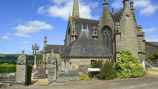 Eine historische Kirche mit einem hohen Turm, filigraner Steinmetzarbeit und einem Friedhof im Vordergrund.