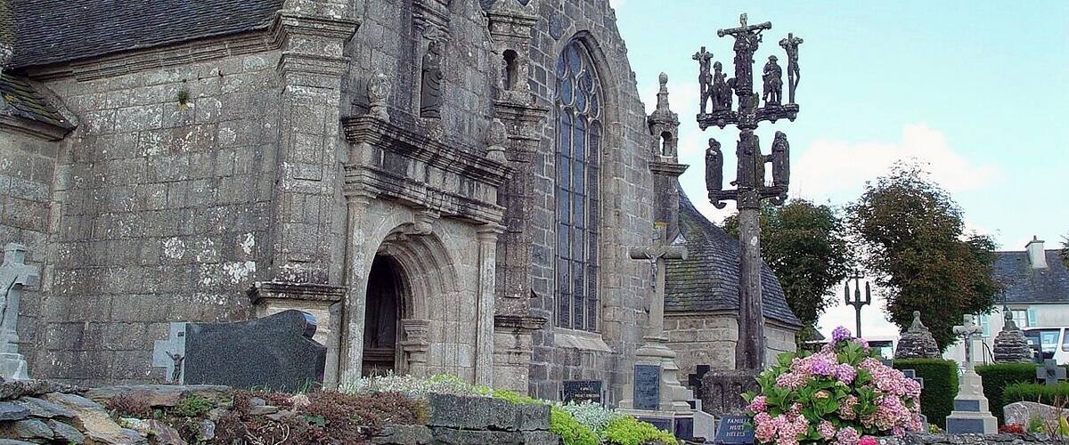 A historic stone church with a tall bell tower and a large arched entrance.