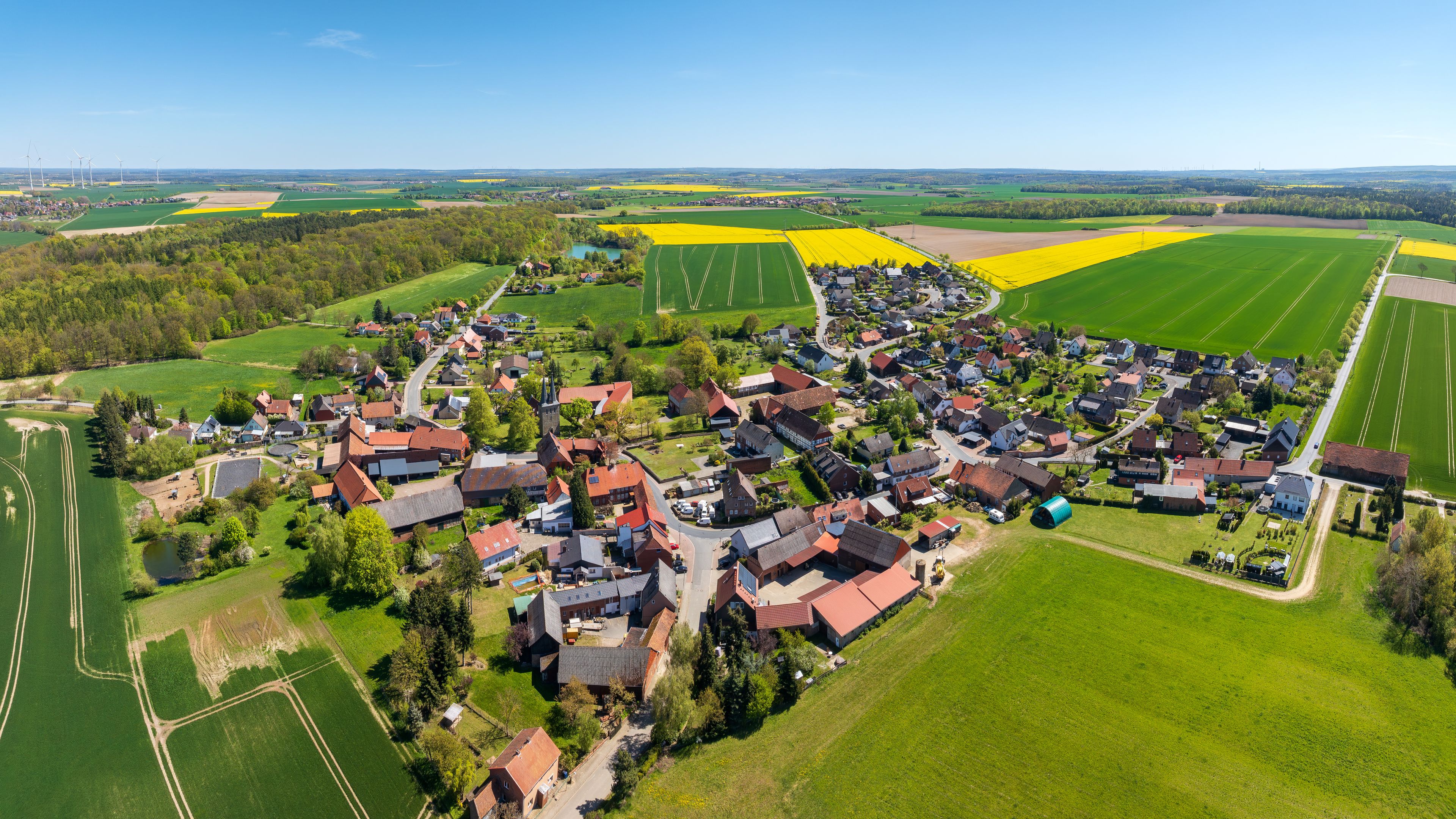 Un village rural avec des maisons, des champs et des éoliennes.