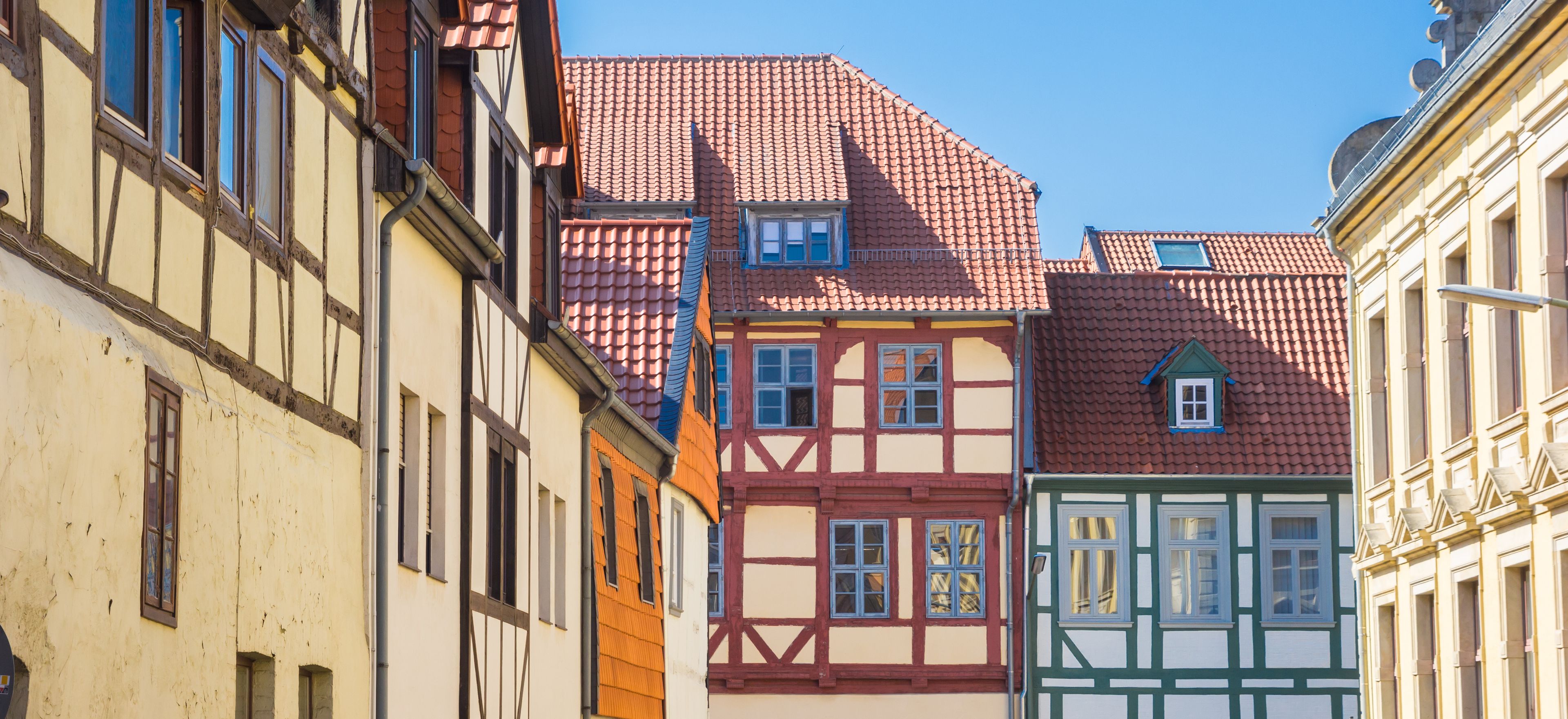 Une rangée de maisons traditionnelles à colombages, avec des toits couverts de tuiles rouges et des façades blanches.