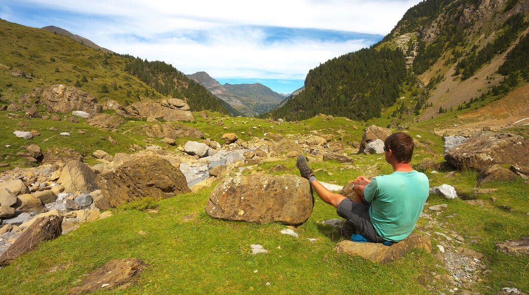 Resting tourist with one leg leaning against the stone in the mountain valley nearby resort of Gavarnie, Pyrenees