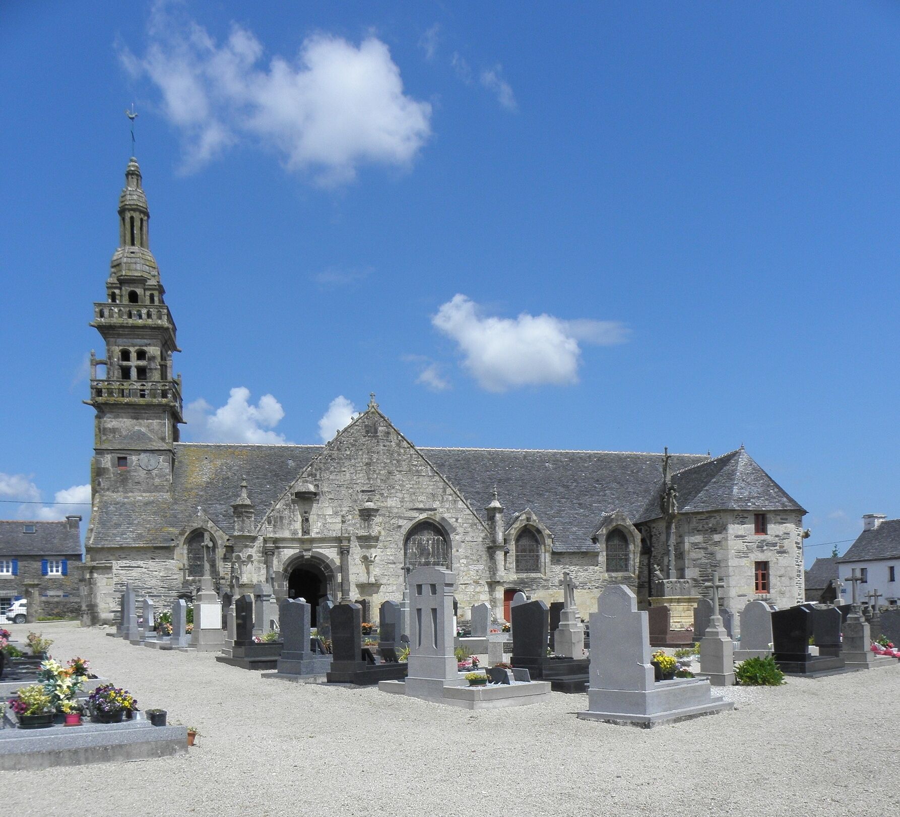 A historic church with a tall bell tower and a cemetery in front.