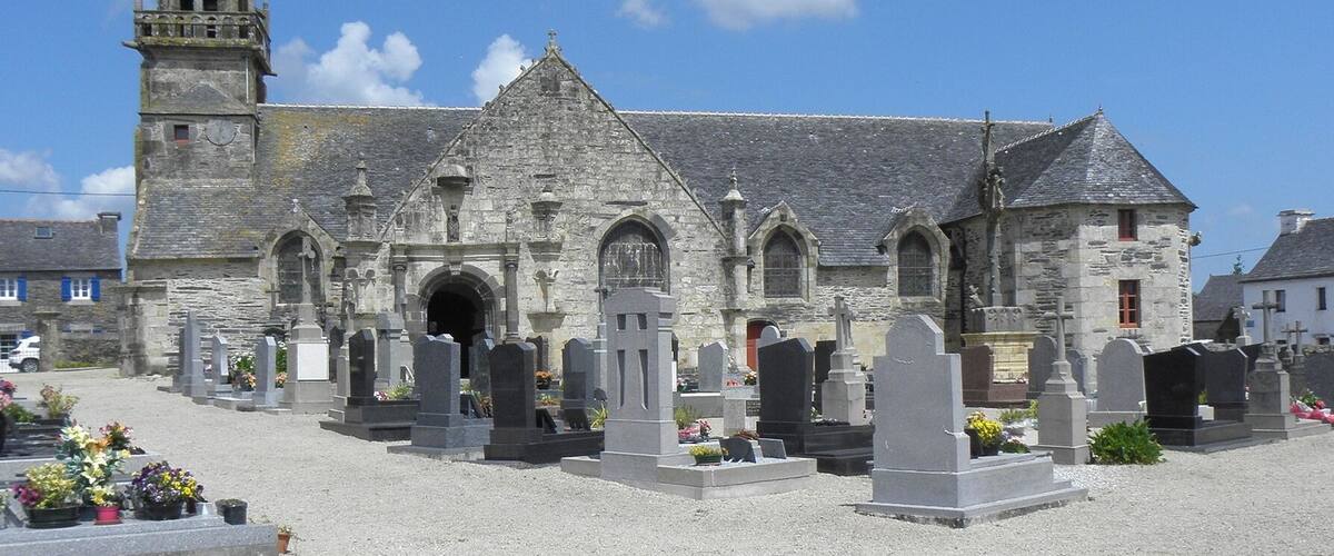 A historic church with a tall bell tower and a cemetery in front.