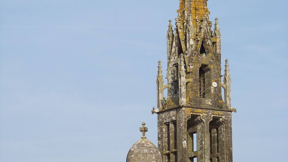 A tall, ornate church tower with intricate architectural details and a weathered appearance.