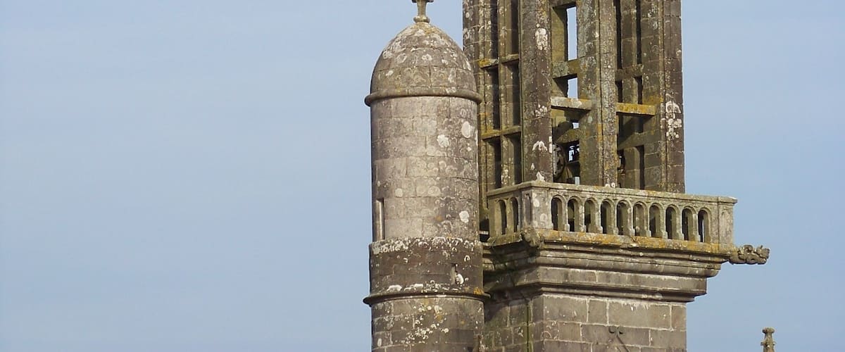 A tall, ornate church tower with intricate architectural details and a weathered appearance.