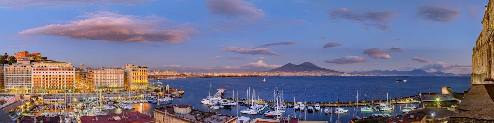 Naples, Italy. Splendid panoramic view from Castel dell'Ovo over the city and Borgo Marinari after sunset. Marina on Via Partenope with luxury hotels. Mount Vesuvius in the distance. 2012-12-19.