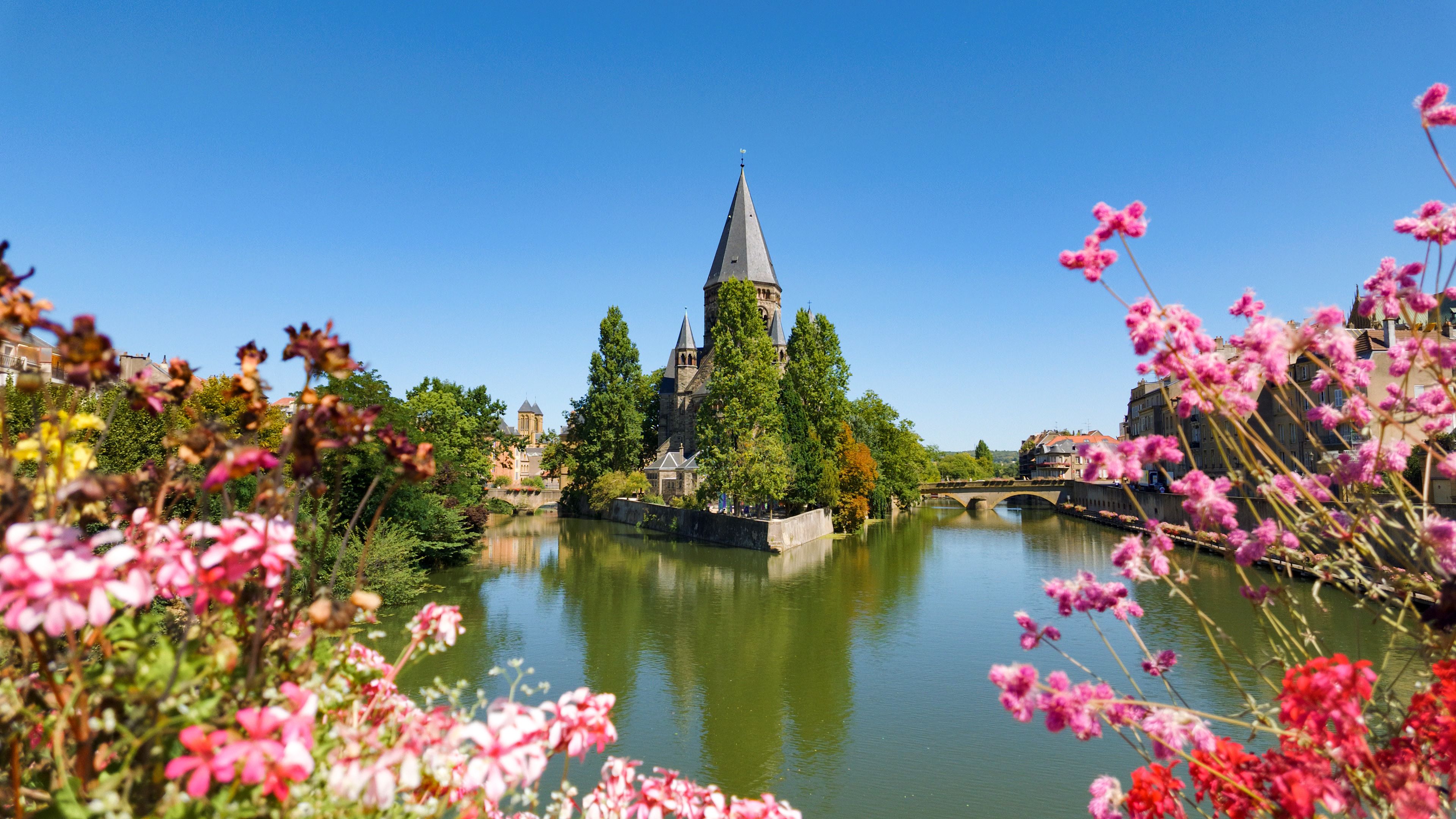Une église historique dotée d’un clocher imposant, une rivière et une végétation luxuriante environnante.