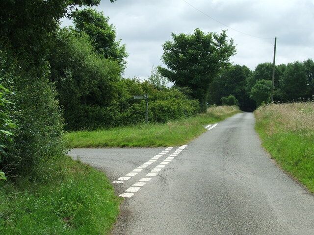 A rural road with a dashed white line, surrounded by greenery and trees.
