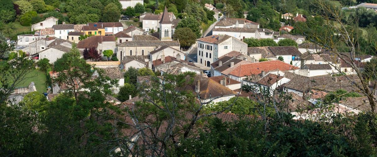 A picturesque village nestled in a valley surrounded by lush greenery and rolling hills.