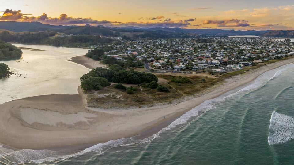 A coastal town with a beach, a river, and mountains in the background.