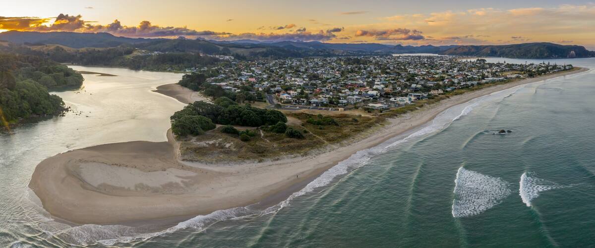 A coastal town with a beach, a river, and mountains in the background.