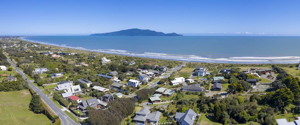 A coastal town with houses, a beach, and a mountain in the distance.