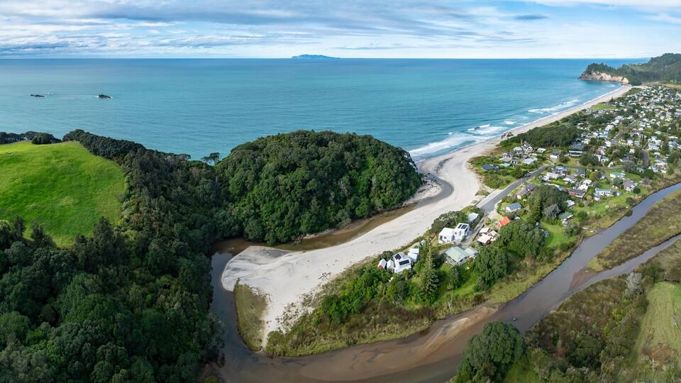 A coastal landscape with a beach, a river, and a residential area.